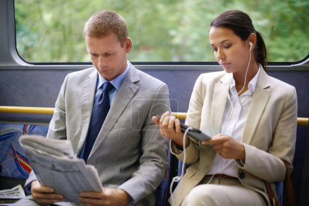 Photo for Bus, business people and commute to work on transportation, reading newspaper and tablet for info. Woman, earphones and online for social media or travel, newsletter and man for article on transit. - Royalty Free Image