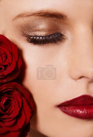 Photo for Closeup of face, makeup and beauty with roses, red lipstick and gold eyeshadow with lashes for cosmetics. Shimmer, shine and bold aesthetic, romantic flowers and cropped with skin and cosmetology. - Royalty Free Image