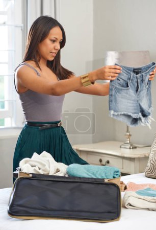 Photo for Travel, clothes and woman packing luggage for vacation, planning and ready for holiday with bag. Jeans, person and suitcase in bedroom for trip preparation, journey or tourism with shorts at home. - Royalty Free Image