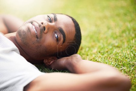 Photo for Portrait, relax and black man on grass in garden of summer home for peace, wellness or mindfulness. Face, nature and field with happy young person lying on green ground from above for break or rest. - Royalty Free Image