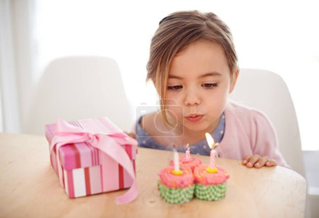 Téléchargez les photos : Cupcakes, bougies et fille avec anniversaire, cadeau et célébration avec bonheur, bonbons et maison. Enfance, enfant ou excité avec le dessert ou cadeau avec la fête ou boîte avec des bonbons ou surprise avec paquet. - en image libre de droit