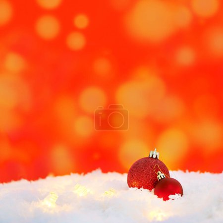 Téléchargez les photos : Noël, lumières et boules pour la décoration sur neige avec espace maquette en hiver sur un fond rouge. Noël, glace et sphère festive, boules et ornements pour les fêtes chrétiennes lors d'une fête. - en image libre de droit