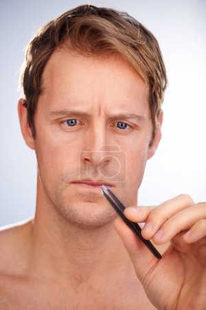 Man, tweezers and eyebrow hair removal in studio for grooming, skincare or mockup space. Male person, tool and plucking for dermatology microblading for transformation, cosmetic or white background.