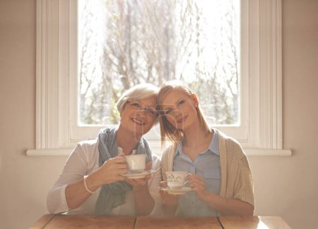 Téléchargez les photos : Portrait, femme heureuse et mère âgée buvant du thé au petit déjeuner le matin, collant et souriant à la maison. Visage, mère aînée et fille avec tasse à café à table, amour et famille à la maison ensemble. - en image libre de droit