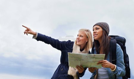 Photo for Woman, friends and pointing with map for direction or location on hiking adventure together in nature. Young female person, hiker or team with travel guide for destination, route or outdoor path. - Royalty Free Image