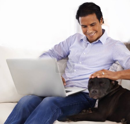 Man, dog and face with laptop on sofa for bonding, playing or happiness with remote work in home. Animal, person and cuddle with smile on couch in living room for research, comfort and love for puppy.