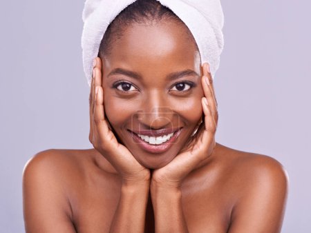 Téléchargez les photos : Cheveux, serviette et portrait de femme noire en studio pour soins de la peau, bien-être ou soins du corps sur fond violet. Beauté, nettoyage et mains sur le visage du modèle féminin africain avec cosmétique, brillance ou éclat. - en image libre de droit