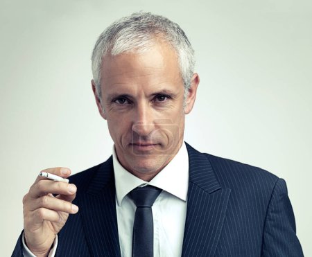 Photo for Portrait, suit and mature man smoking cigarette with salesman in studio isolated on a gray background. Face, fashion and serious businessman with tobacco, ceo or manager in vintage clothes in Canada. - Royalty Free Image