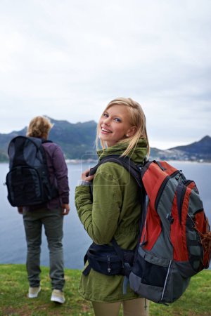 Photo for Happy couple, portrait and hiking with backpack for adventure, travel or outdoor journey together in nature. Young man and woman with smile and bag for trekking, explore or fitness by the ocean coast. - Royalty Free Image