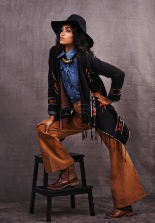 Photo for Culture, cowgirl or woman thinking in studio, wild west and cool fashion or clothing on grey background. Native American person, western lady and stylish model with pride, boho style and chair stool. - Royalty Free Image