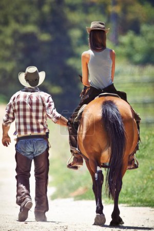 Foto de Espalda de mujer, vaquero o equitación en granja rural como ecuestre para el entrenamiento, el deporte o el aprendizaje. Caminar, enseñar o personas en Texas, ambiente al aire libre o estable para practicar en silla de montar. - Imagen libre de derechos