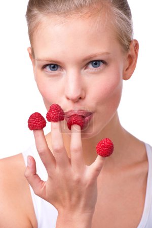 Portrait, breakfast and raspberries on fingers of woman in studio isolated on white background for diet. Face, health and food on hand of young person eating fruit for weight loss, detox or nutrition.