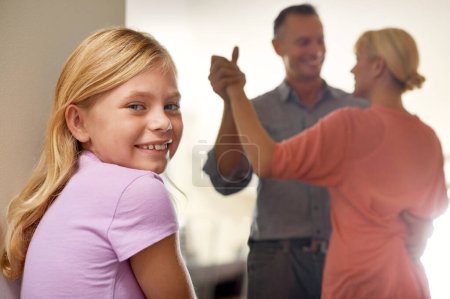 Photo for Girl, portrait and smile while parents dance in home, childhood and happy on weekend. Female person, happy couple and love or bonding for fun, smile and calm mindset to relax or confident in joy. - Royalty Free Image