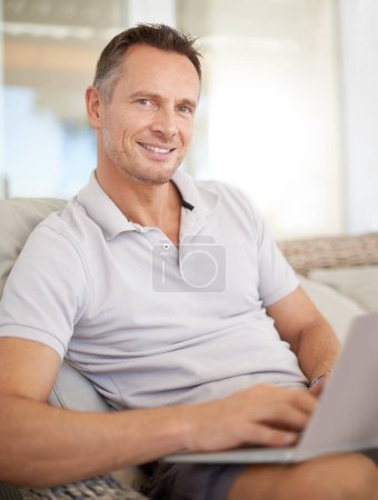 Photo for Man, laptop and portrait on patio in home, chair and typing with search for movies on website. Person, computer and relax on couch, scroll and happy for streaming subscription on holiday at apartment. - Royalty Free Image