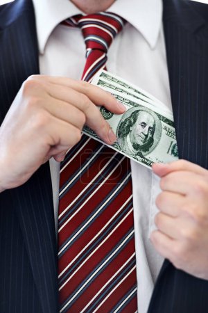 Photo for Businessman, hands and money bribe in pocket for fraud, scam or secret on a white studio background. Closeup of employee with cash, dollar bills or finance in bribery, deal or financial exchange. - Royalty Free Image