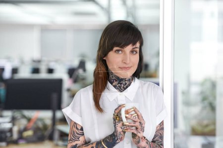 Photo for Smile, tattoos and business woman with coffee in office with positive, good and confident. Grunge, cappuccino and portrait of professional edgy creative designer with ink skin standing in workplace - Royalty Free Image