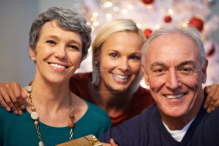 Photo for Christmas, tree and senior family in portrait with love, happy and gratitude for holiday and tradition at night. Face of elderly parents with daughter and gift, present and celebration at their home. - Royalty Free Image