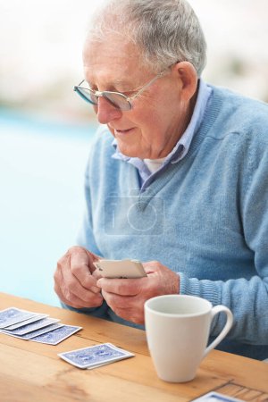 Homme âgé, café et cartes à jouer sur la table pour le poker, se détendre et heureux à la retraite. Personne âgée, grand-père et boisson avec réflexion, passe-temps et stratégie amusante sur le patio à la maison en buvant du thé.