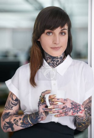 Photo for Tattoos, coffee and portrait of business woman in office with positive, pride and confident attitude. Grunge, smile and edgy female creative designer with ink skin standing in modern workplace - Royalty Free Image