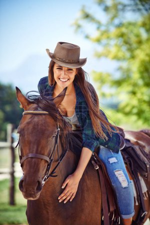 Foto de Retrato de mujer, sonrisa o equitación en granja rural como ecuestre para entrenamiento, deporte o sombrero de vaquero. Mujer feliz, silla de montar o agricultura occidental en Texas o el medio ambiente, al aire libre o estable. - Imagen libre de derechos