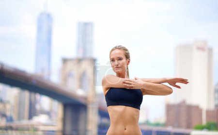 Photo for Woman, stretching arms for workout in city for wellness or wellbeing, physical health and stress relief. Girl active to warm up muscle, exercise and fitness for sports runner or athlete in New York - Royalty Free Image