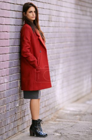 Photo for Winter, fashion and woman on wall with jacket in city and travel with cool style in red coat. Streetwear, clothes and girl outdoor on building background with confidence and pride in New York morning. - Royalty Free Image