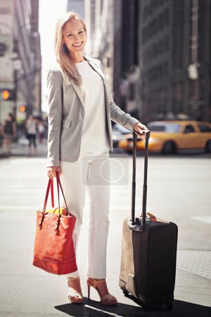 Téléchargez les photos : Femme d'affaires, bagages et portrait dans la route avec le sourire pour le voyage avec marche, costume et extérieur. Personne, heureux et bagages pour voyager en ville sur le trottoir du métro par des immeubles gratte-ciel à New York. - en image libre de droit