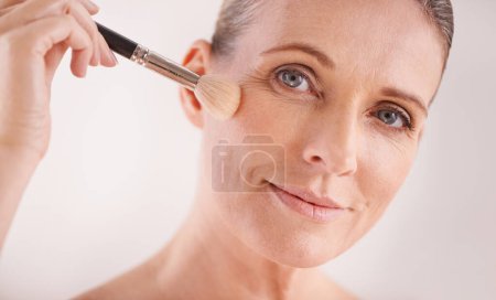 Photo for Makeup brush, face and portrait of woman in studio for cosmetic, self care and facial glow routine. Beauty, foundation and mature female person with cosmetology tool for treatment by white background. - Royalty Free Image