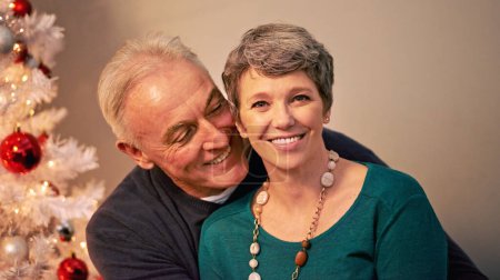 Photo for Christmas, portrait and happy senior couple with love, care and support together in a home on holiday. Tree, retirement and marriage with smile and hug in house with celebration and romance with joy. - Royalty Free Image