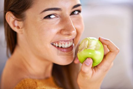 Photo for Woman, portrait and apple for hunger in home, organic fiber and fruit for wellness. Happy female person, vitamins and minerals for healthy living, eating snack and vegan food in closeup for diet. - Royalty Free Image