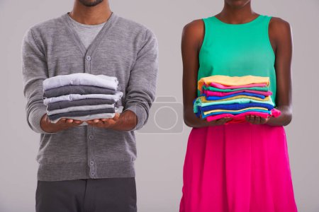 Photo for Hands, couple and clothes for laundry, cleaning and hygiene in studio isolated on a gray background. Man, woman and people with fabric for housework, housekeeping or pile of linen for chores together. - Royalty Free Image