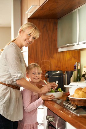 Photo for Mother, daughter and cooking a salad in portrait, happy and kitchen for healthy meal in home. Girl, mommy and support in learning for child development, love and bonding with nutrition and vegan diet. - Royalty Free Image