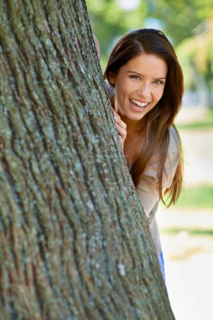 Photo for Woman, park and tree with hide, smile and portrait with happiness and green fun for nature. Lady, laugh and sun with grass, forest and happy for excited playful summer with optimism and sunshine. - Royalty Free Image