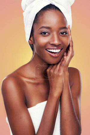 Haartuch, Porträt und schwarze Frau im Studio für Hautpflege, Wellness oder Körperpflege auf orangefarbenem Hintergrund. Schönheit, Reinigung oder Hände im Gesicht eines afrikanischen weiblichen Modells mit kosmetischer, glänzender oder glühender Haut.