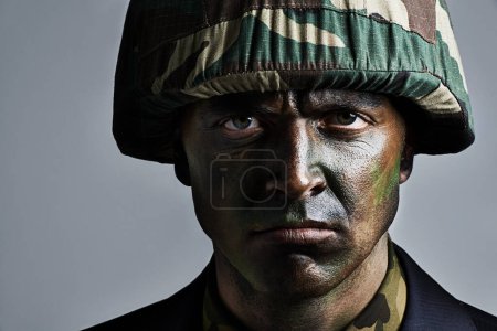 Photo for Man, portrait and soldier with camouflage for military war or battle on a gray studio background. Closeup of male person, army or commander with face paint or helmet in undercover disguise on mockup. - Royalty Free Image
