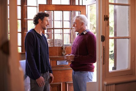 Photo for Son, senior dad and talking in home by front door with advice, chat and bonding with connection. Men, elderly father and adult child with conversation for love, visit and holiday in family house. - Royalty Free Image