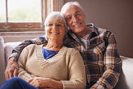 Téléchargez les photos : Couple sénior, heureux et portrait dans le canapé avec câlin, amour et connexion dans le salon pour la retraite. Femme âgée, vieil homme et embrasser sur le canapé-salon avec fierté, soin et sourire dans l'appartement. - en image libre de droit