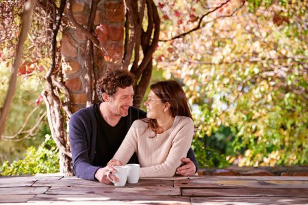 Photo for Spring, relax and couple embrace with coffee cups on table in nature, environment and together for romance. Partners, woman and man with hand from girl, hug and touch for love in marriage and park. - Royalty Free Image