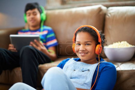 Photo for Tablet, children and portrait of girl with headphones in streaming, music or audio book with her brother at home. Kids, family and siblings in living room with digital, app or radio, relax or bonding. - Royalty Free Image