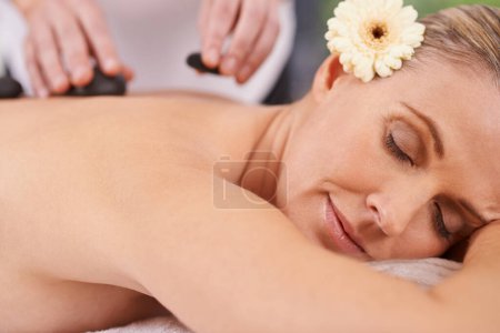 Photo for Woman, spa and hands with hot stone for massage, wellness and relax in hotel. Physical therapy, holistic and female person in holiday or vacation in California for health, peace and back skin detox. - Royalty Free Image