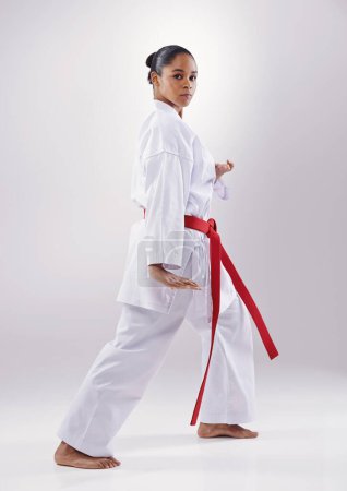 Foto de Mujer, retrato y karate fitness en estudio, guerrero y artes marciales sobre fondo blanco. Persona negra, atleta y cinturón rojo para taekwondo, disciplina y guerrero listo para defensa propia o batalla. - Imagen libre de derechos