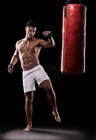 Téléchargez les photos : Kickboxing, homme et entraînement en studio avec sac de boxe pour entraînement, exercice ou combat de compétition avec fitness. Athlète, boxeur et fort pour les arts martiaux avec puissance et seins nus sur fond noir. - en image libre de droit
