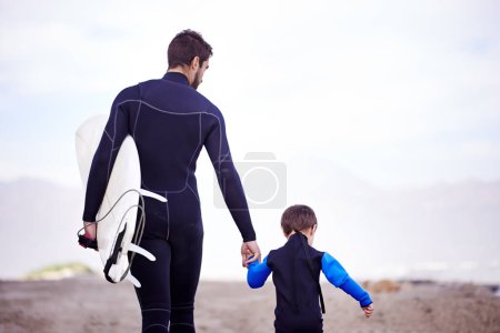 Photo for Surfboard, man and kid on beach, holding hands and walking on outdoor bonding adventure. Nature, father and son at ocean for surfing, teaching and learning together with support, trust and growth - Royalty Free Image