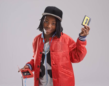 Photo for Music, portrait and child on gray background with cassette for listening to song, audio and radio. Fashion, youth and young African boy with retro tech for track playlist in trendy clothes in studio. - Royalty Free Image