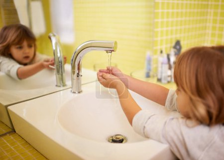 Photo for Girl, bathroom and hands with washing, hygiene and cleaning with mirror at home. Child, faucet and reflection for healthy, development and childhood with morning routine at house for cleanliness. - Royalty Free Image