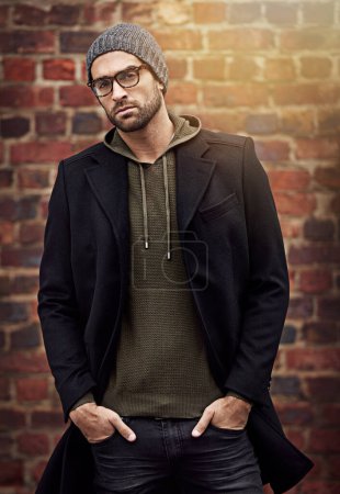 Photo for Man, portrait and winter fashion by brick wall downtown for aesthetic, modern and expression for city culture. Male person, trendy urban outfit for streetwear style for creative career in retail. - Royalty Free Image