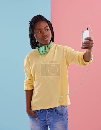Teenager, Junge und Selfie eines Schülers im Studio mit Kopfhörern zum Musikhören in der High School mit Mode. Colorblock, Mockup und Posting in den sozialen Medien mit Selbstvertrauen und Stolz auf das Profilbild.