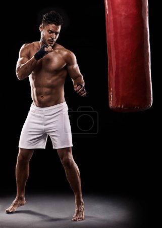 Téléchargez les photos : Kickboxing, homme ou entraînement en studio avec sac de boxe pour l'entraînement, l'exercice ou la lutte de compétition avec fitness. Athlète, boxe ou sérieux pour les arts martiaux avec muscle ou seins nus sur fond noir. - en image libre de droit