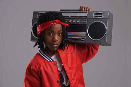 Photo for Child, hip hop and portrait with radio for cool music and dance in a studio with urban clothing. Fashion, African kid and boombox with trendy clothes and rap swag with confidence and grey background. - Royalty Free Image