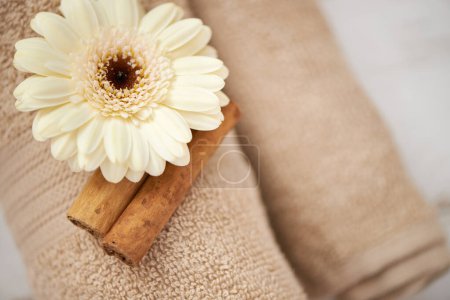 Photo for Detail, closeup and flower on towel in spa for luxury service in hospitality at hotel on holiday or vacation. Floral, cinnamon and offer object in accommodation for wellness treatment on table. - Royalty Free Image